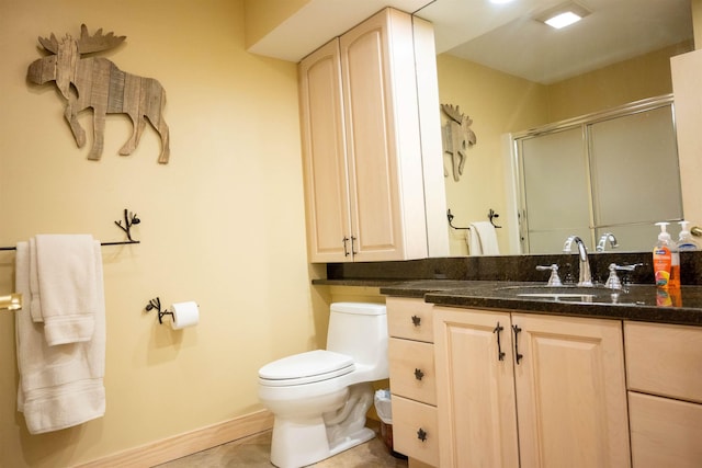 bathroom with baseboards, a shower stall, toilet, and vanity