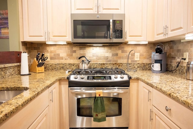 kitchen featuring appliances with stainless steel finishes, light stone counters, and backsplash