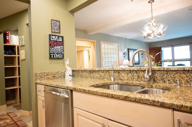 kitchen featuring stainless steel dishwasher, a sink, decorative light fixtures, and light stone countertops