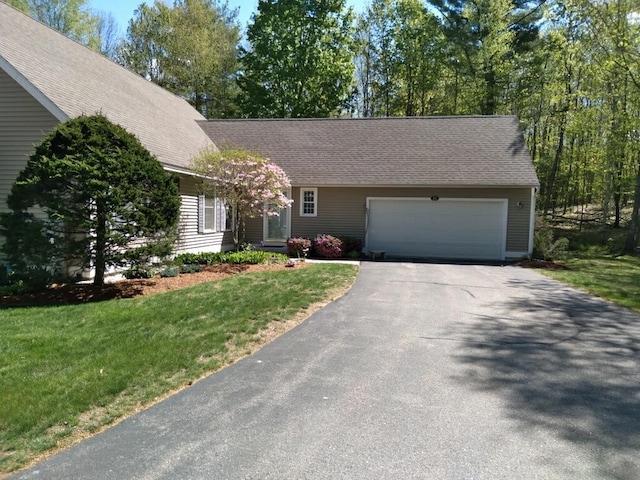 view of front of property featuring a garage, a front yard, roof with shingles, and driveway