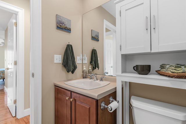 bathroom with toilet, wood finished floors, and vanity