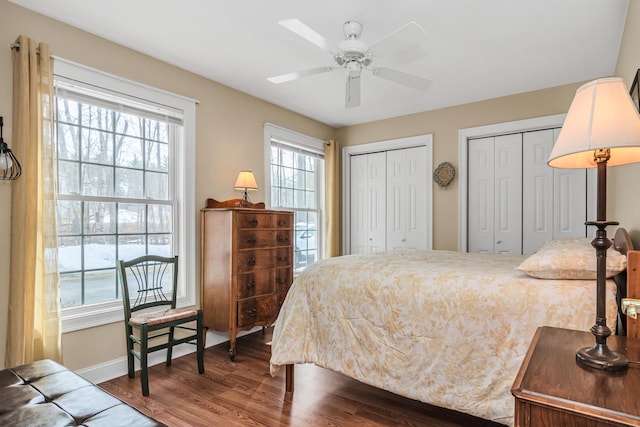 bedroom with ceiling fan, baseboards, multiple closets, and wood finished floors