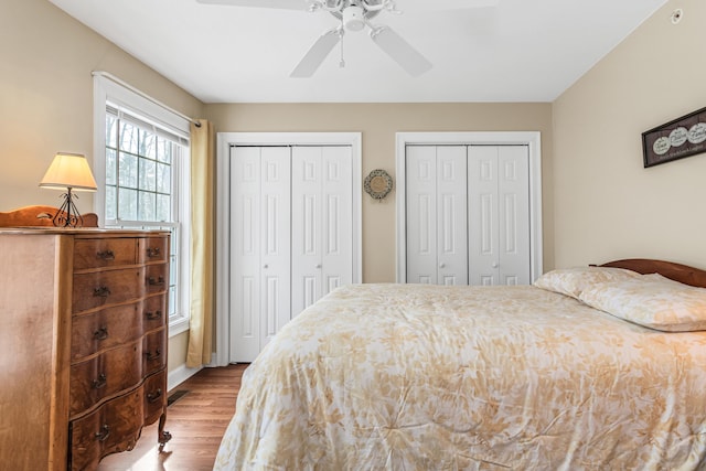 bedroom featuring two closets, a ceiling fan, and wood finished floors