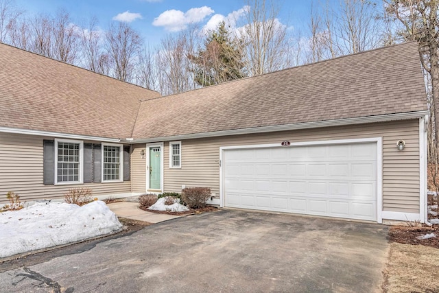 view of front of property featuring an attached garage, driveway, and roof with shingles