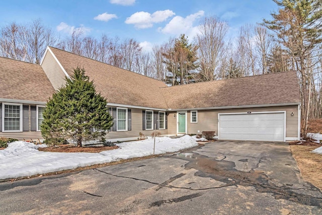 view of front of home with driveway, a shingled roof, and a garage