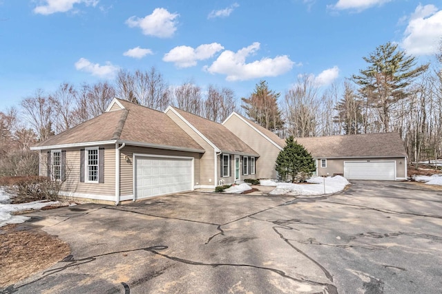 ranch-style home featuring a garage and roof with shingles