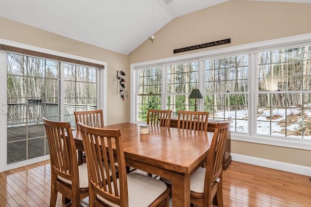 dining area with lofted ceiling, baseboards, and light wood finished floors