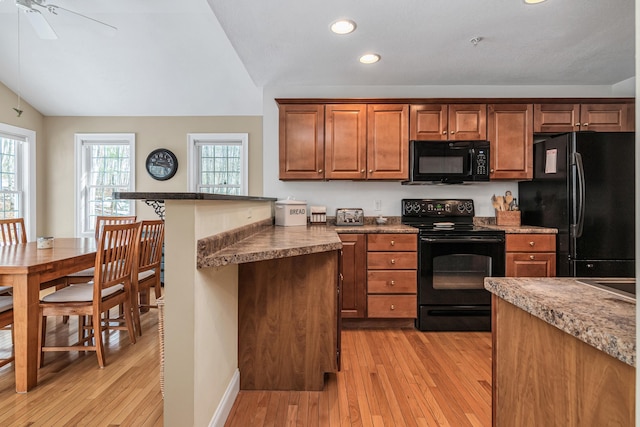 kitchen featuring recessed lighting, black appliances, vaulted ceiling, light wood-style floors, and brown cabinets