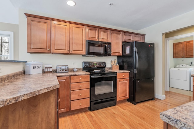 kitchen featuring black appliances, light wood-style floors, brown cabinetry, light countertops, and washing machine and clothes dryer