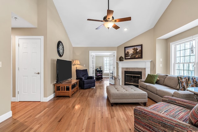 living room with baseboards, a healthy amount of sunlight, light wood-type flooring, and a tile fireplace