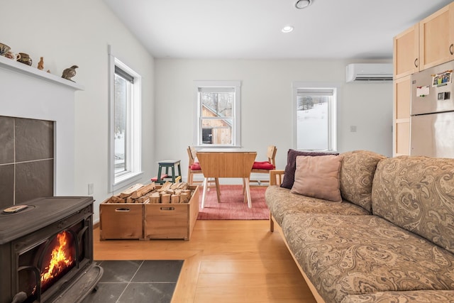 living area featuring light wood-type flooring, a wall unit AC, a wood stove, and recessed lighting