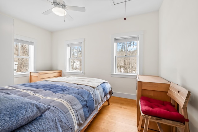 bedroom featuring baseboards, multiple windows, attic access, and light wood-style floors