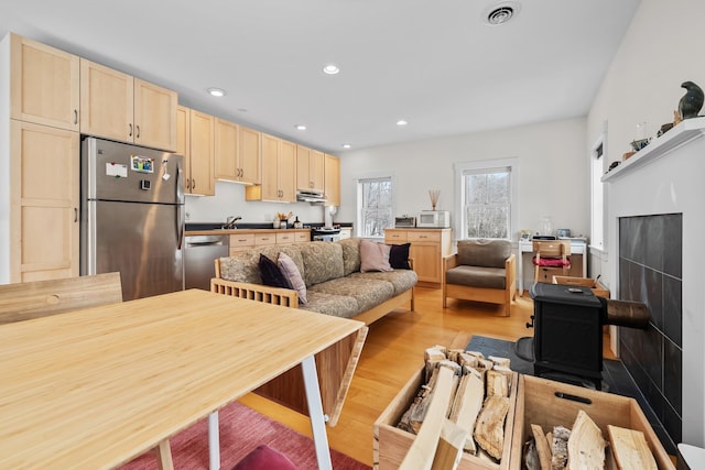 kitchen featuring light wood finished floors, recessed lighting, light brown cabinetry, appliances with stainless steel finishes, and under cabinet range hood