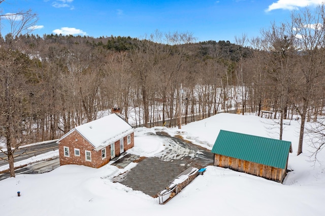 snowy aerial view featuring a wooded view