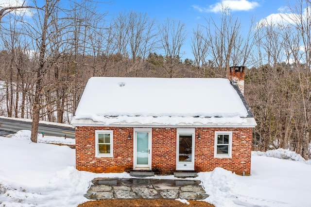 view of front of house featuring entry steps, brick siding, and a chimney