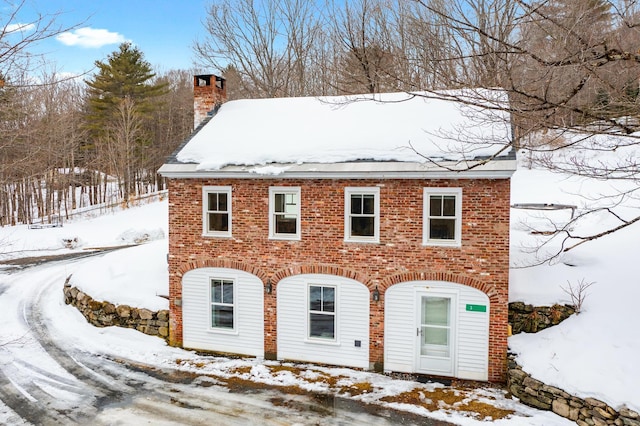 view of front of home featuring a chimney and brick siding