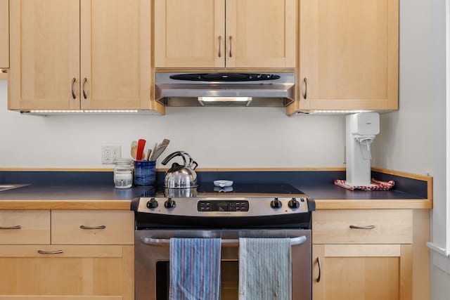 kitchen with light brown cabinetry, under cabinet range hood, and stainless steel electric stove