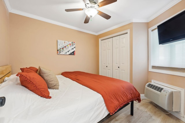 bedroom featuring an AC wall unit, ornamental molding, a closet, and light wood-type flooring