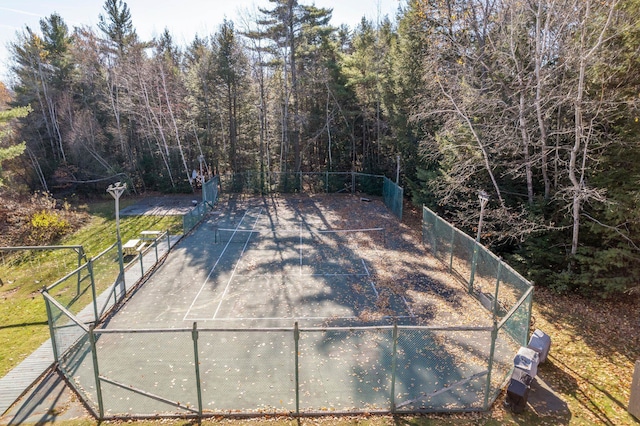 exterior space with a tennis court and fence