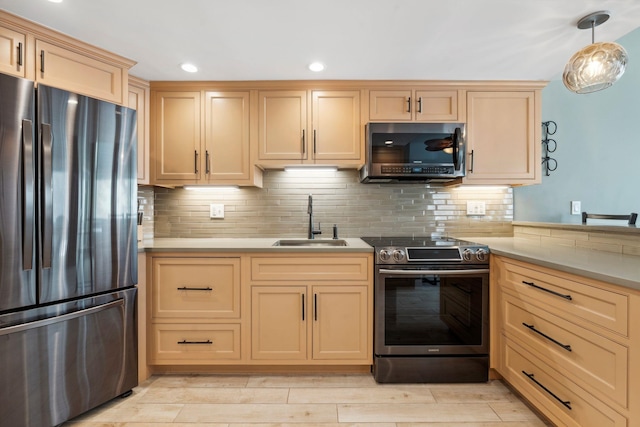 kitchen with light brown cabinets, appliances with stainless steel finishes, decorative backsplash, and a sink