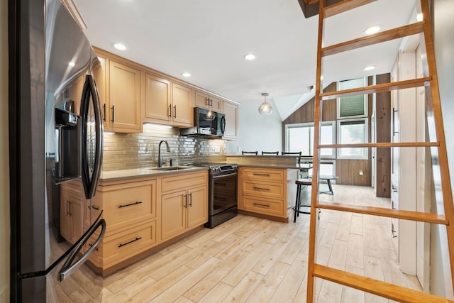 kitchen with decorative backsplash, light wood-style flooring, appliances with stainless steel finishes, a peninsula, and a sink