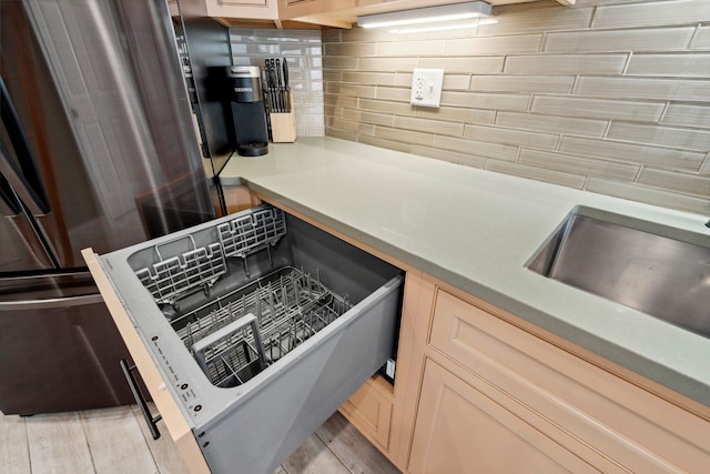 kitchen featuring a sink, light wood finished floors, light countertops, and backsplash