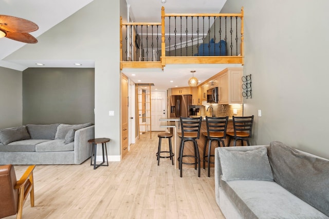 living room featuring light wood-style flooring, high vaulted ceiling, baseboards, and recessed lighting