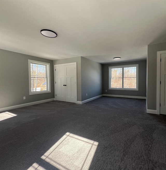 interior space featuring dark carpet and baseboards