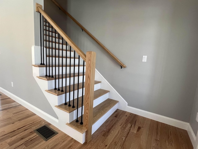 stairway with wood finished floors, visible vents, and baseboards