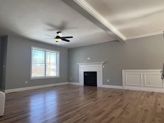 unfurnished living room featuring baseboards, a ceiling fan, wood finished floors, a fireplace, and beam ceiling