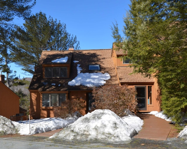 view of front of house with a shingled roof and a chimney