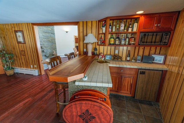 bar with dark wood-style floors, a baseboard radiator, and indoor wet bar