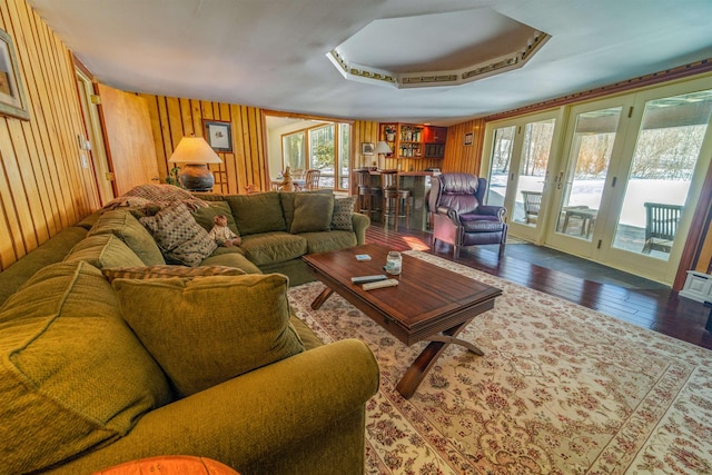 living room featuring french doors, wood-type flooring, and wooden walls