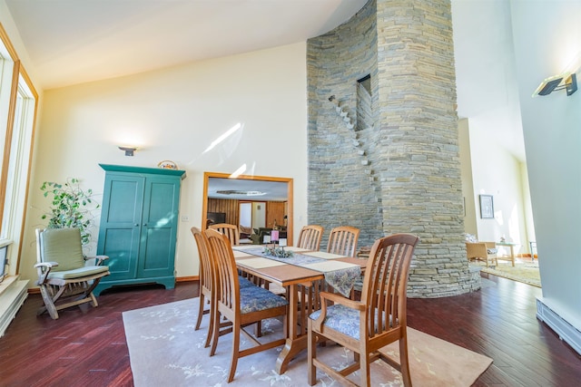 dining space with high vaulted ceiling and dark wood-type flooring