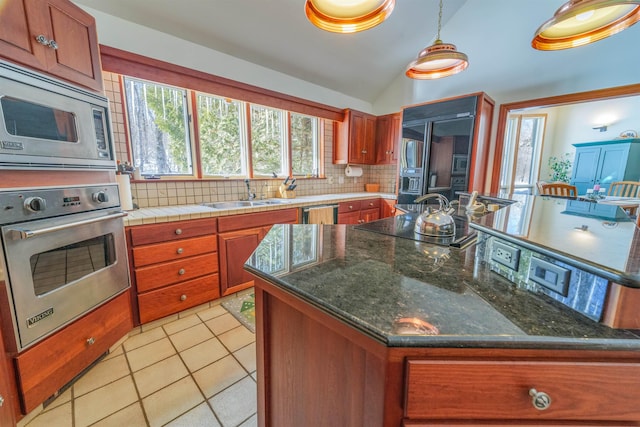 kitchen featuring light tile patterned floors, stainless steel appliances, a sink, vaulted ceiling, and backsplash