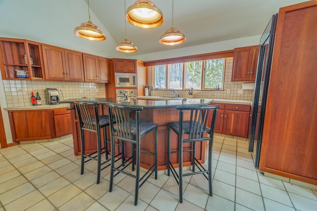 kitchen with tasteful backsplash, a kitchen breakfast bar, vaulted ceiling, stainless steel appliances, and light tile patterned flooring