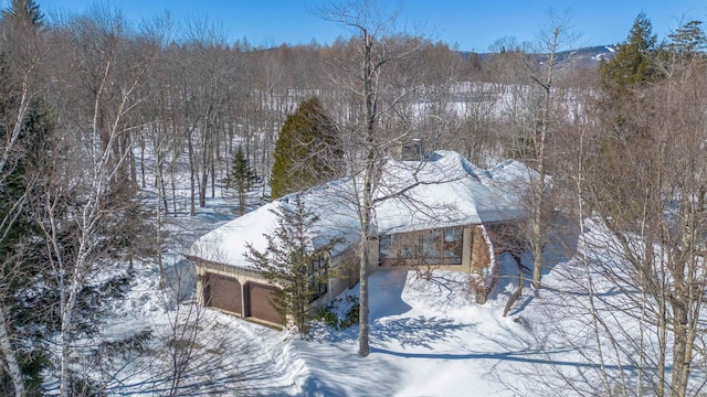 snowy aerial view featuring a forest view