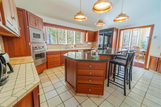 kitchen featuring light tile patterned flooring, stainless steel appliances, a breakfast bar, a sink, and tasteful backsplash