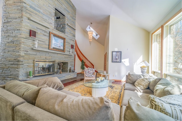 living area featuring high vaulted ceiling, a stone fireplace, and wood finished floors