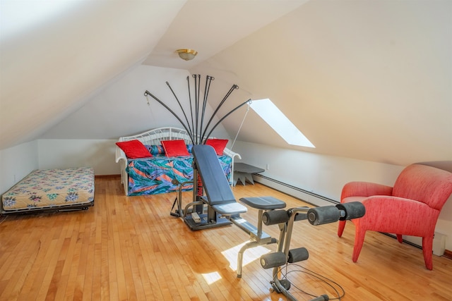 exercise area with lofted ceiling with skylight, a baseboard radiator, and hardwood / wood-style flooring