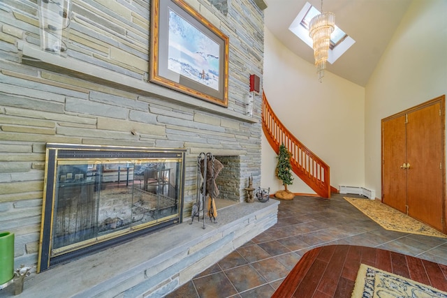 unfurnished living room featuring high vaulted ceiling, a stone fireplace, dark tile patterned floors, a skylight, and baseboard heating