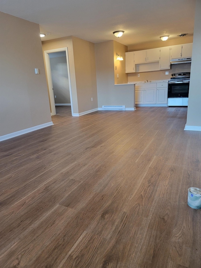 unfurnished living room with a baseboard heating unit, dark wood-type flooring, visible vents, and baseboards