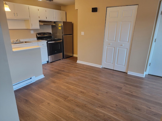 kitchen with white cabinets, a baseboard radiator, stainless steel appliances, light countertops, and under cabinet range hood