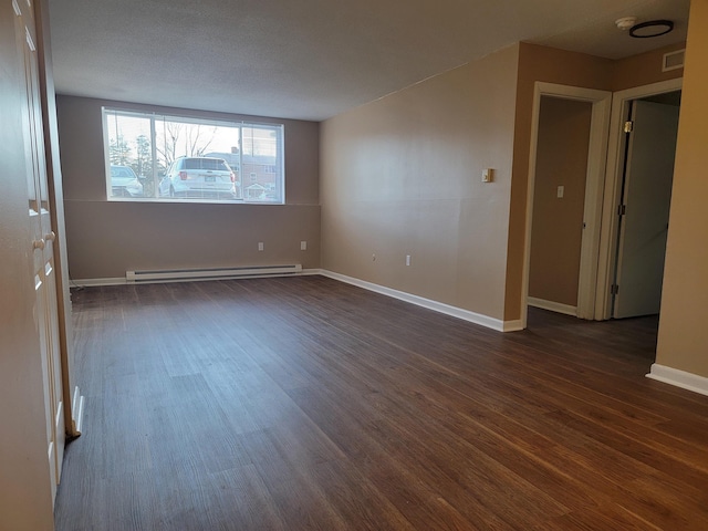 empty room featuring a baseboard heating unit, dark wood-style flooring, visible vents, and baseboards