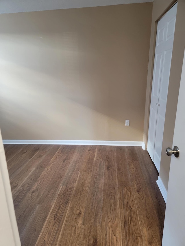 empty room featuring dark wood-type flooring and baseboards