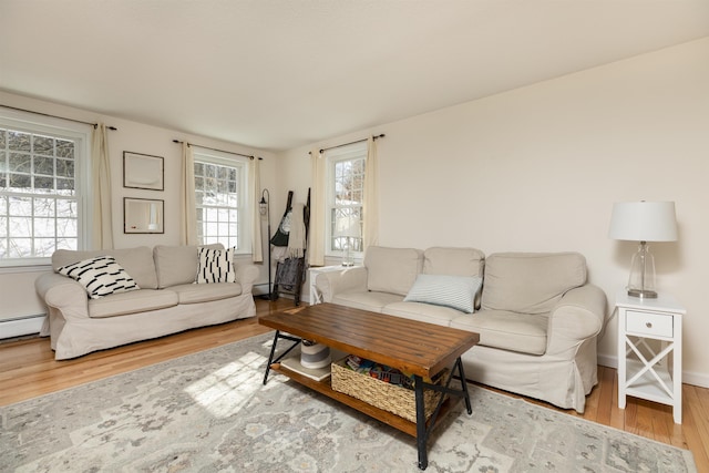 living area featuring baseboards, a baseboard heating unit, and wood finished floors