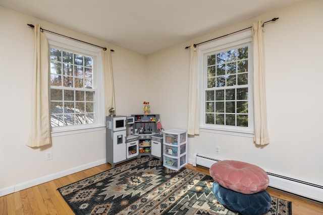 game room with baseboards, baseboard heating, and wood finished floors