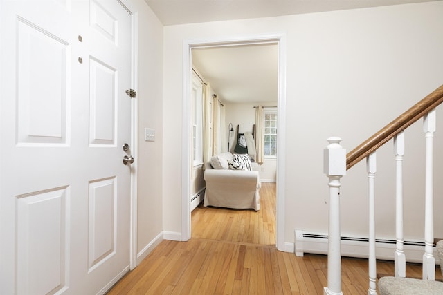 hallway with stairs, light wood-type flooring, baseboards, and a baseboard radiator