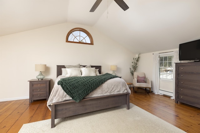 bedroom with lofted ceiling, hardwood / wood-style floors, multiple windows, and a baseboard radiator