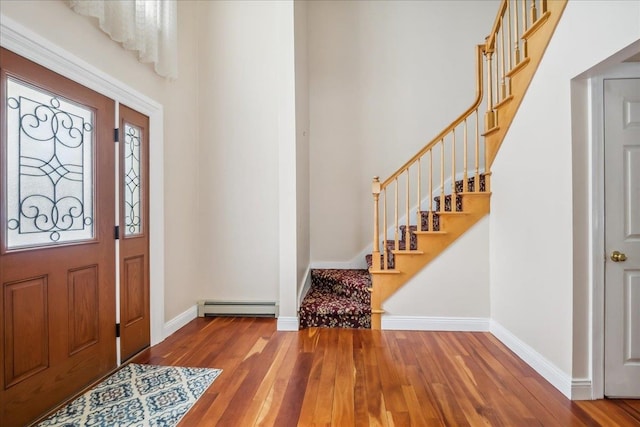 foyer entrance featuring stairway, baseboards, baseboard heating, and wood finished floors